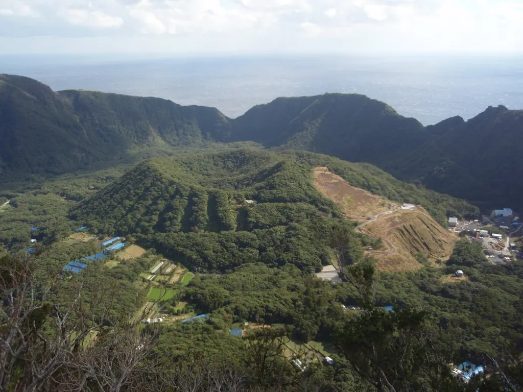 外輪山の上から見下ろした青ヶ島の二重カルデラ。カルデラの底に内輪山の丸山が浮かび、その向こうに太平洋が広がる